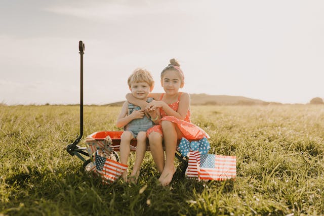 Kids in a wagon with American flags to celebrate the 4th of July